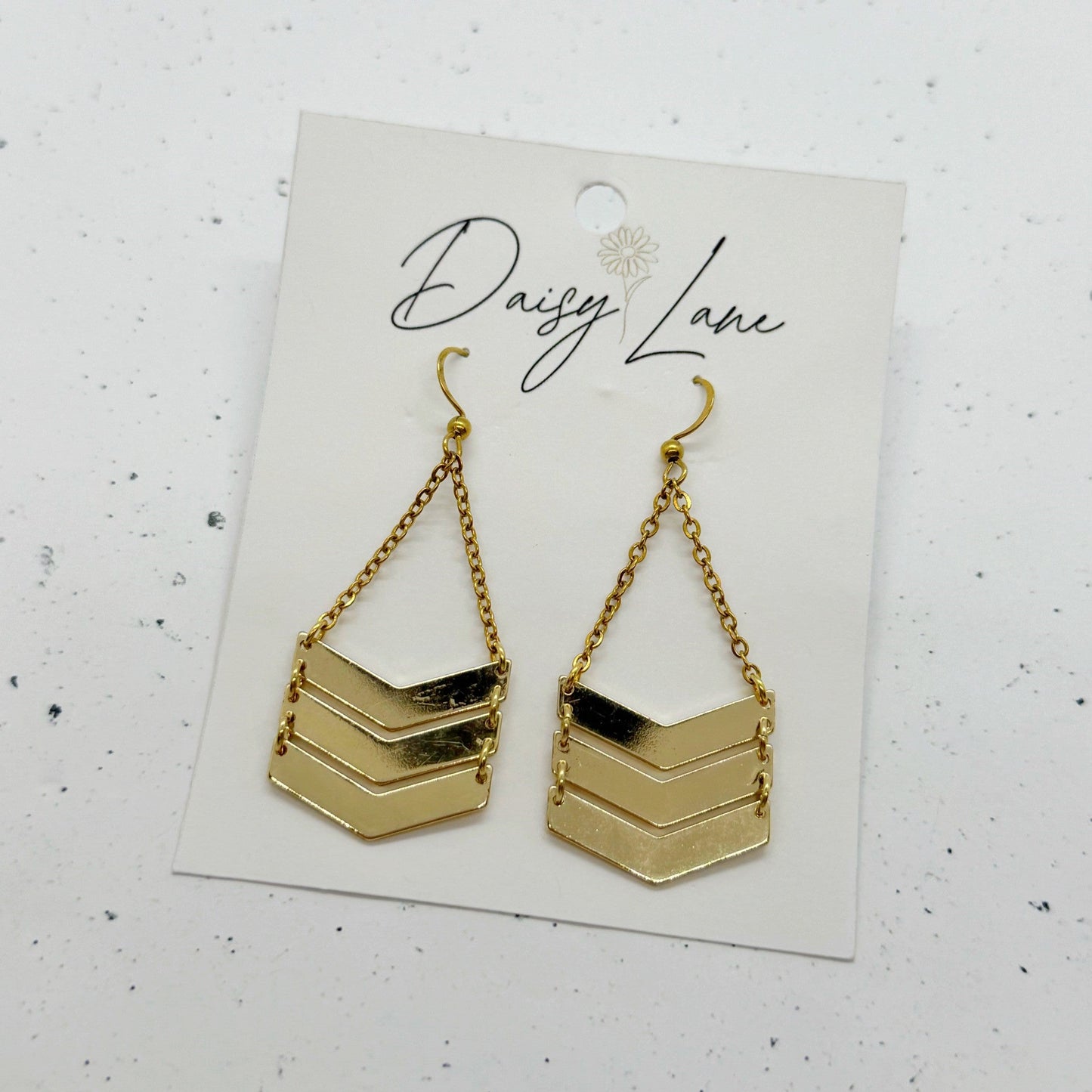 Gold chevron earrings on a 'Daisy Lane' branded card against a white background